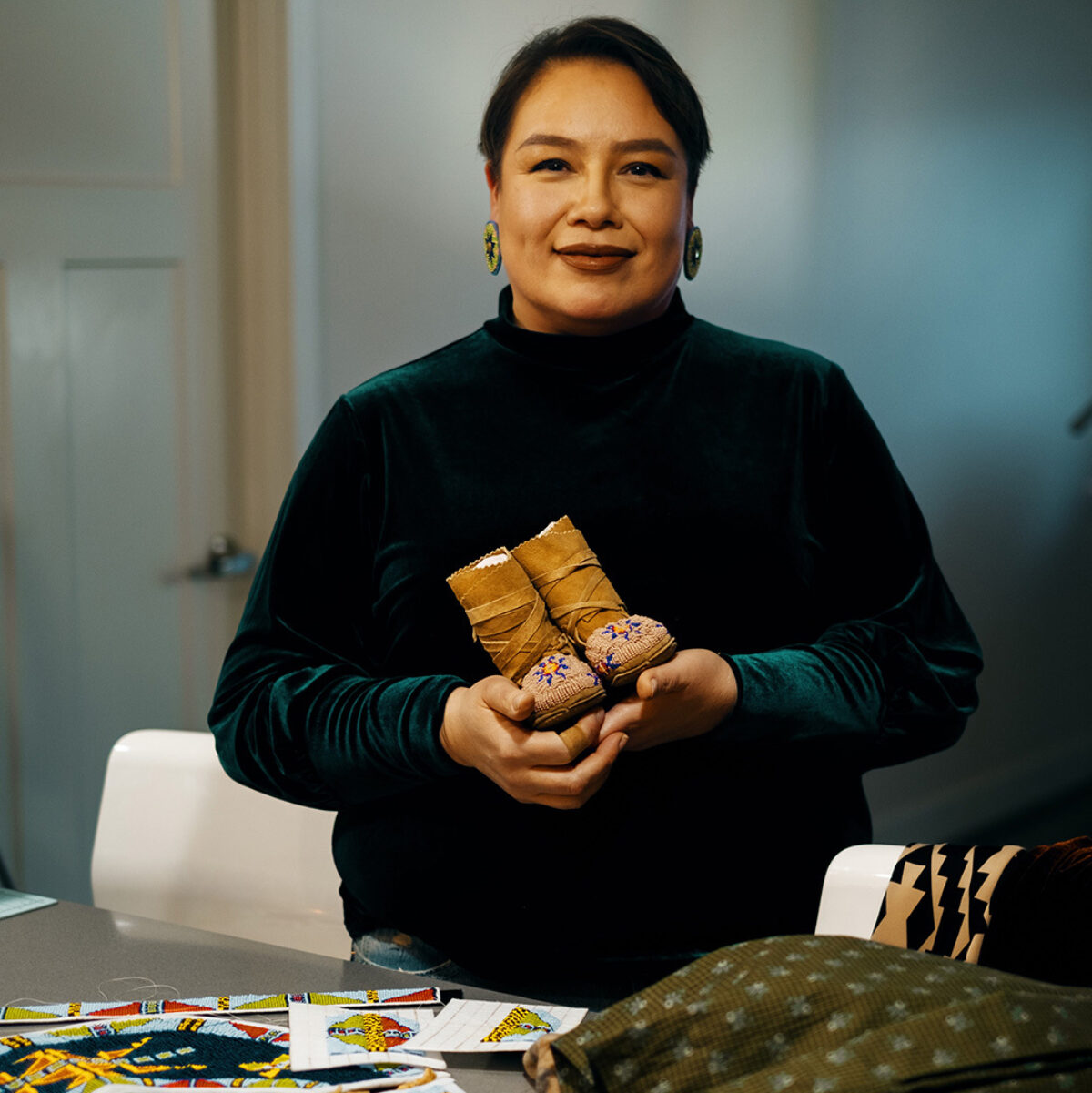 Raine holding the moccasins she made for her daughter