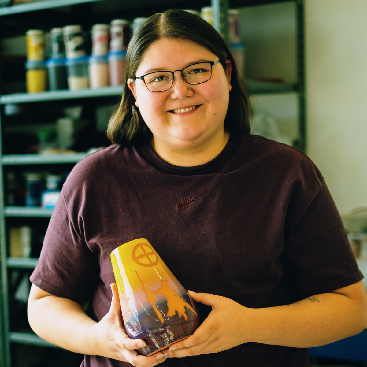 Rochelle smiling with a colorful piece of pottery she made