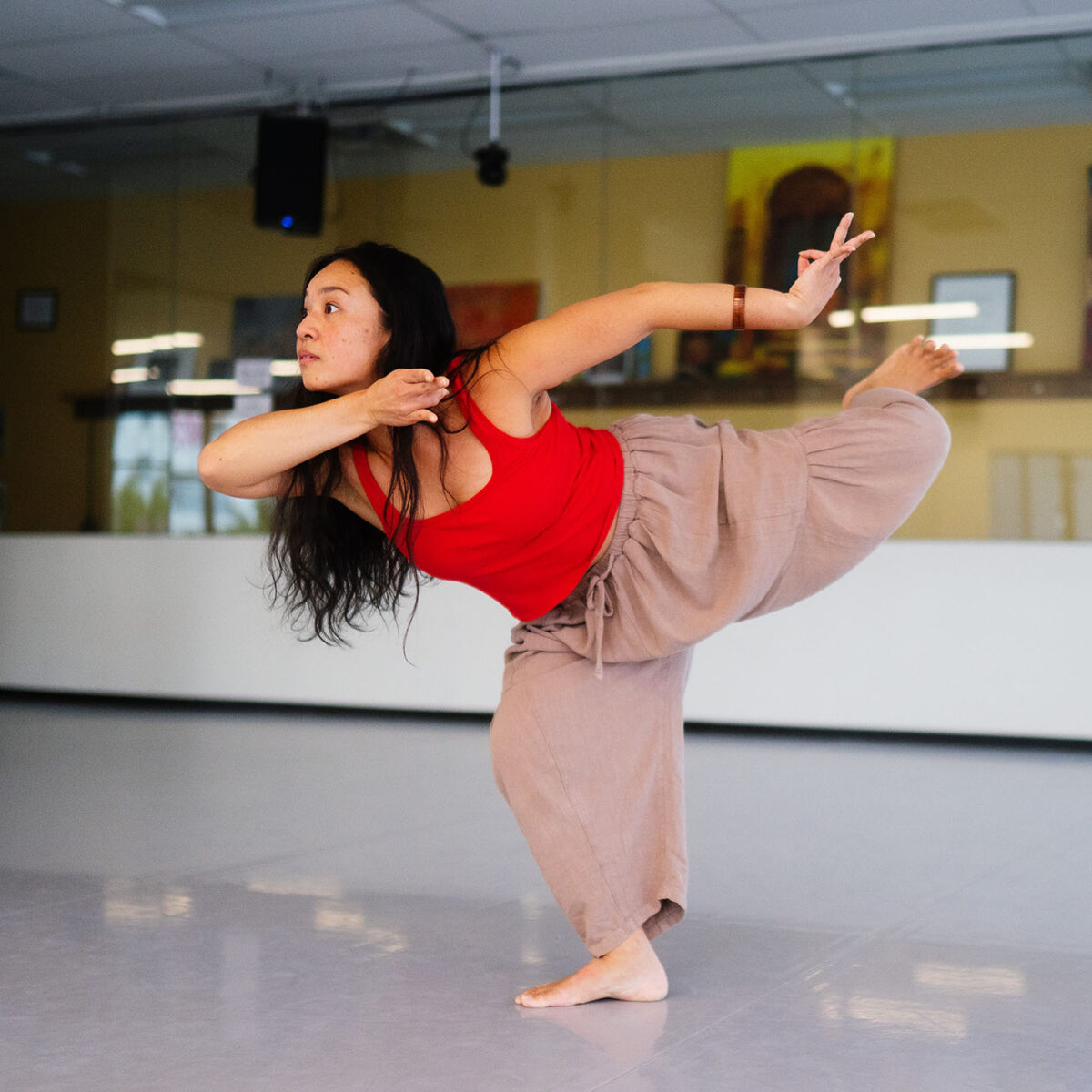 Kealoha gracefully standing on one leg in a dance studio