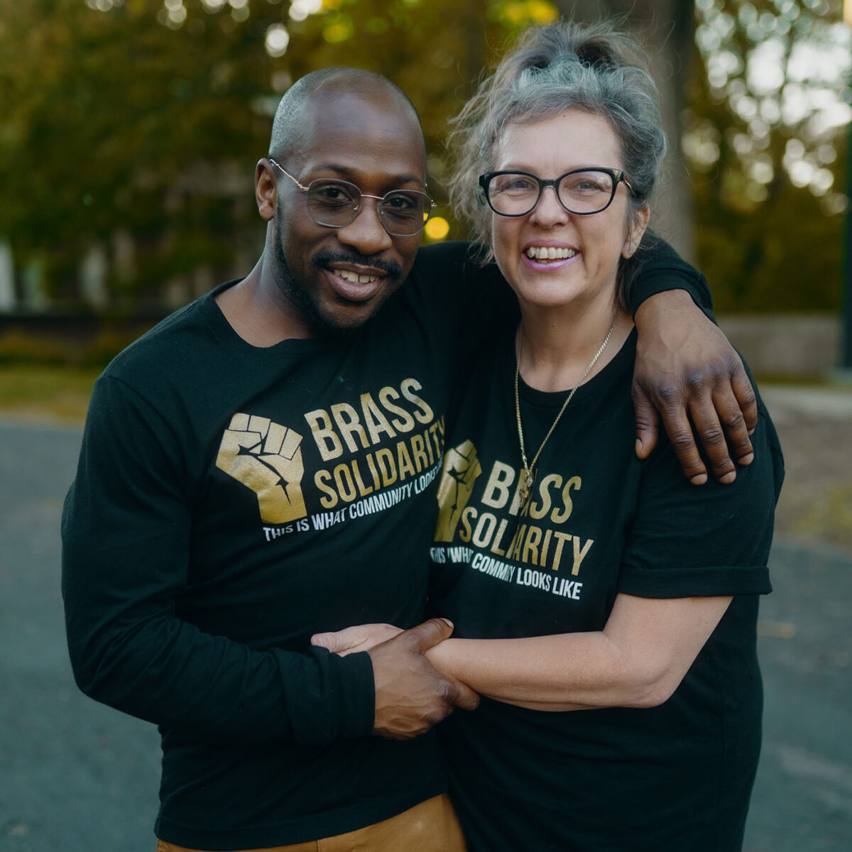 Man and woman standing together wearing Brass Solidarity shirts
