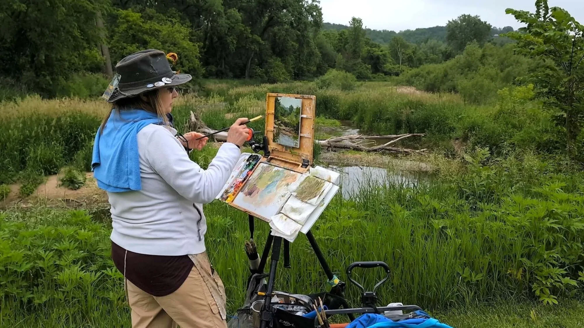 Woman painting a nature scene outdoors