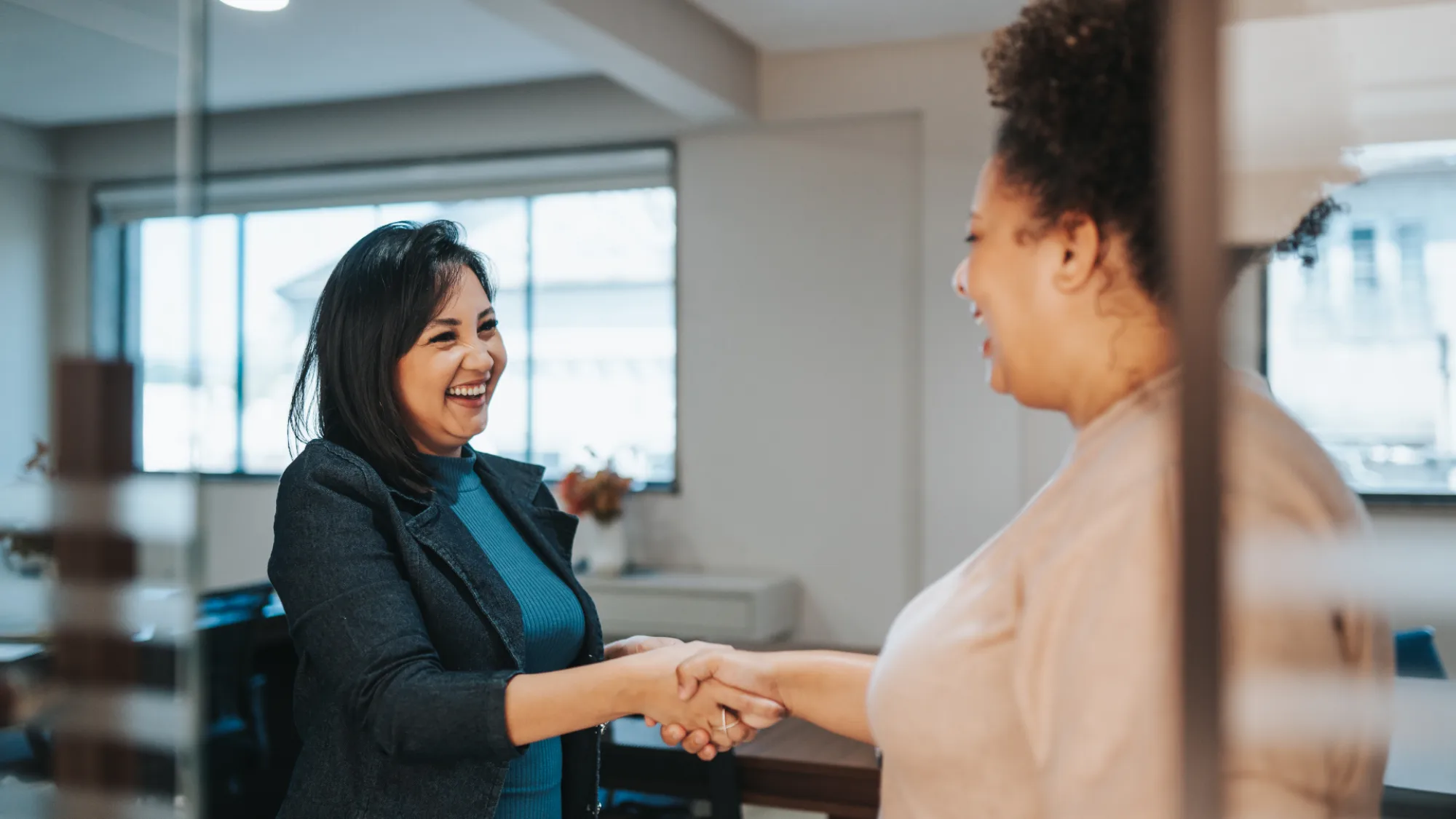 Two women shaking hands in an office