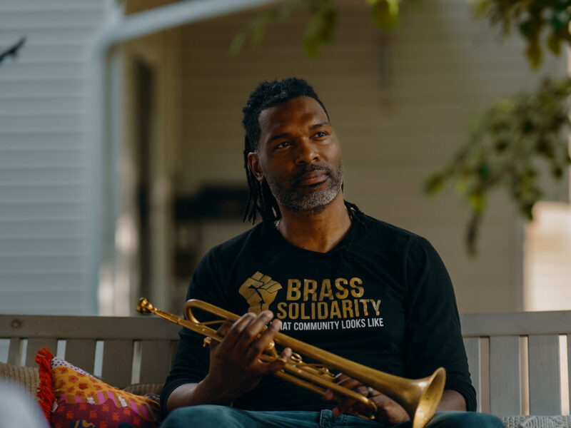 Butchy Austin sitting on a bench swing with his trumpet