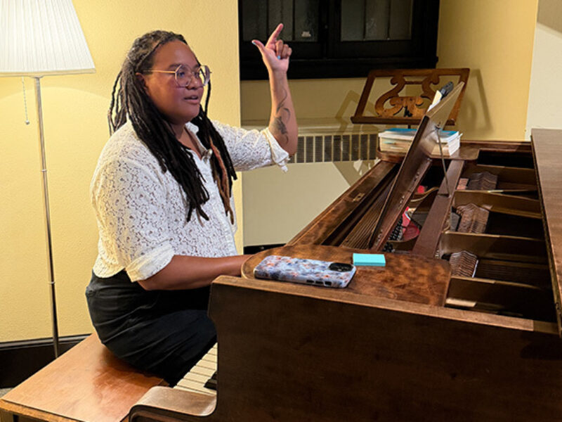 Waigwa seated at the piano and conducting