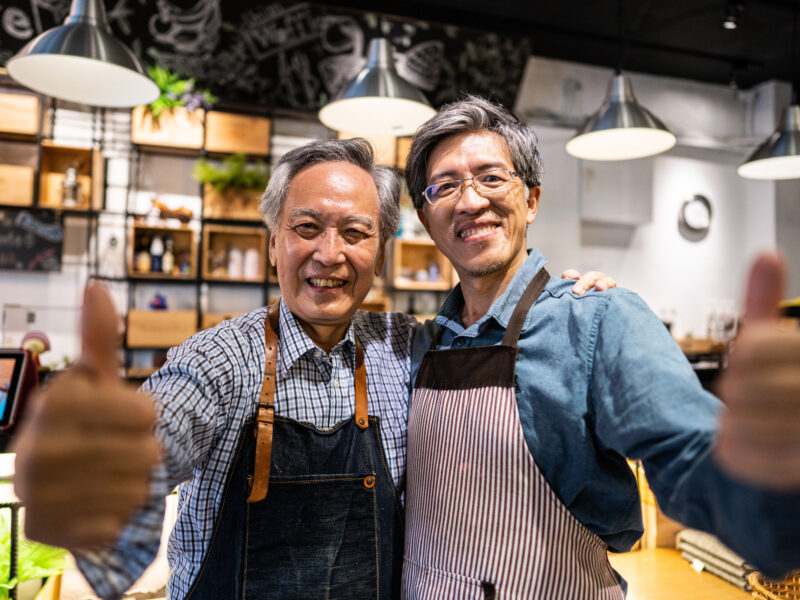 A father and son business owners giving thumbs up