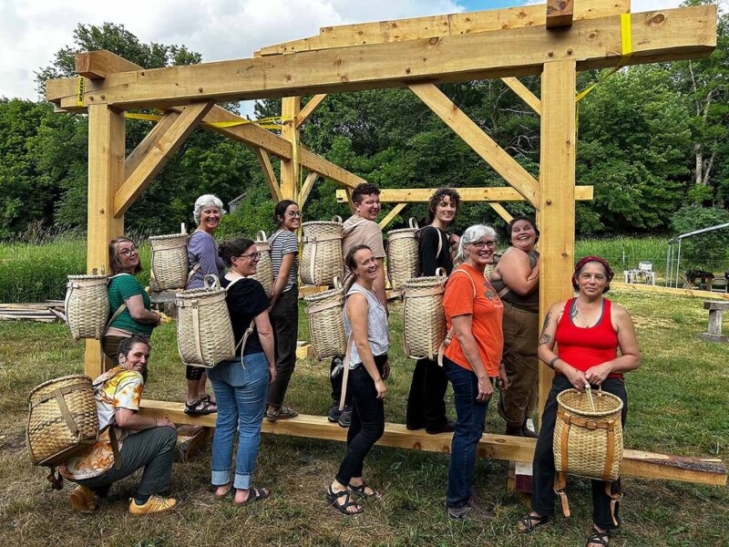 Avon Hills Folk School class standing outside by timber framing
