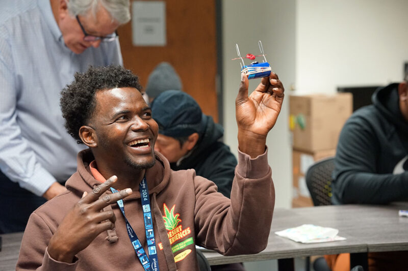 Capi USA man smiling and holding up an art project