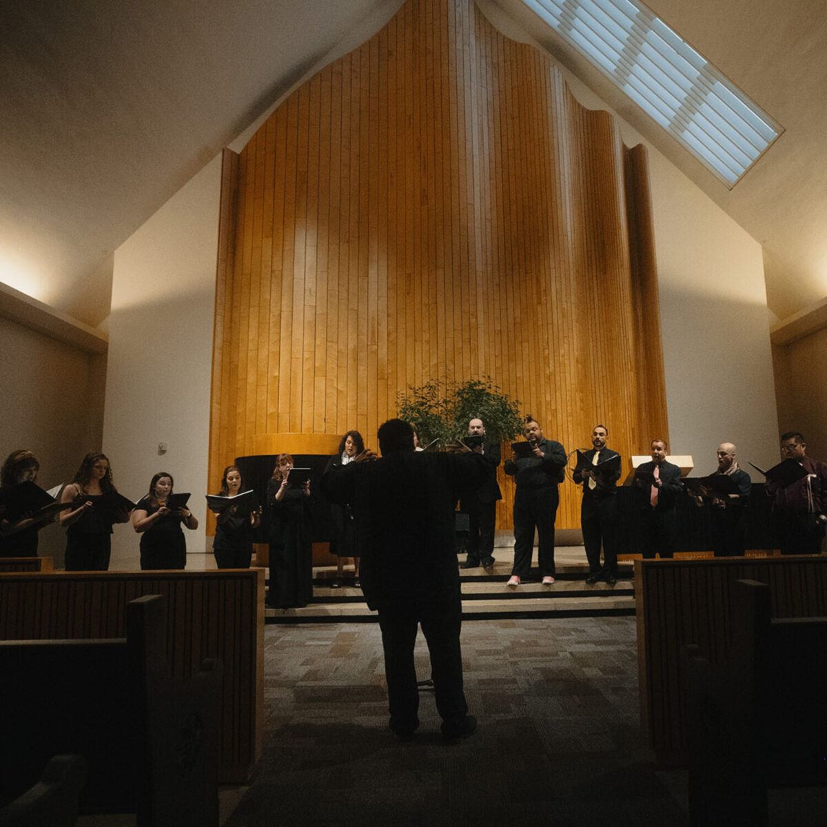 Ahmed conducting the choir in a sun filled sanctuary