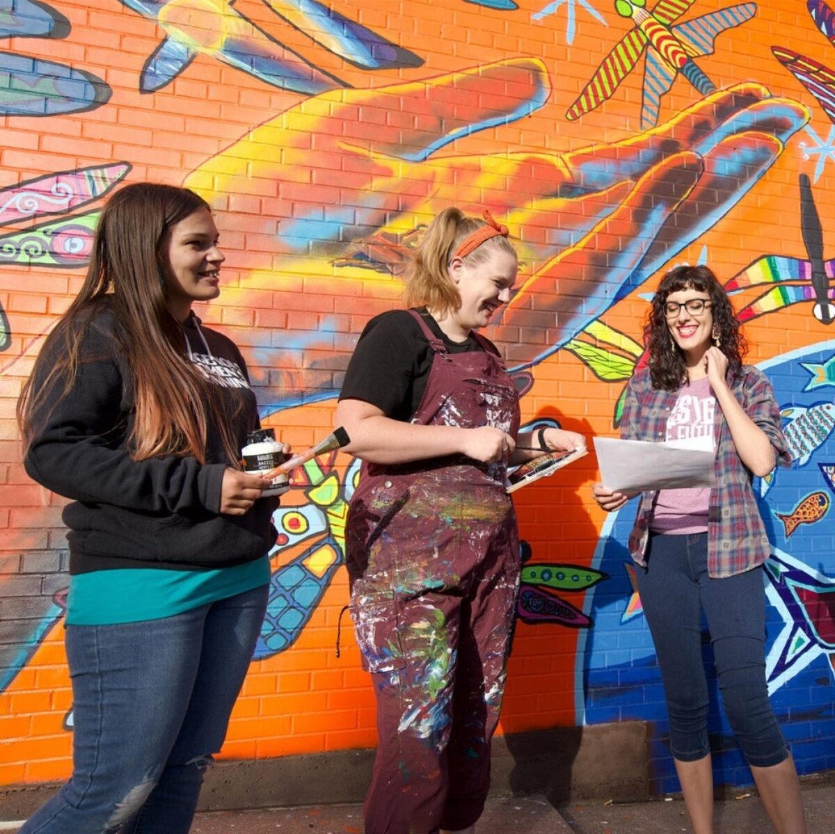 Group of artists in front of a mural